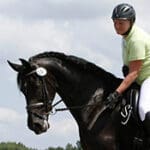 A person riding on the back of a black horse.